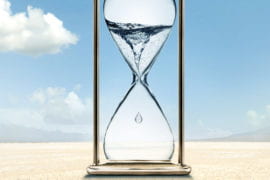 Hourglass holding water sitting in a desert