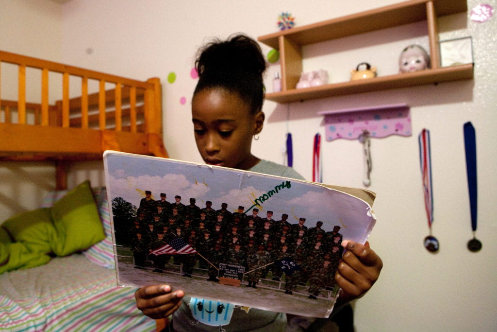 Nyla reads the notes from fellow soldiers on her mom's group photo from basic training