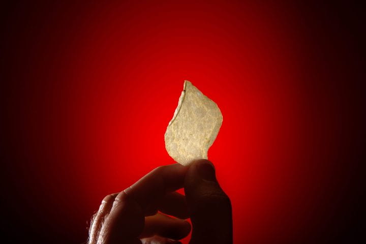 A single potato chip held up