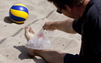 Beach volleyball player icing their ankle
