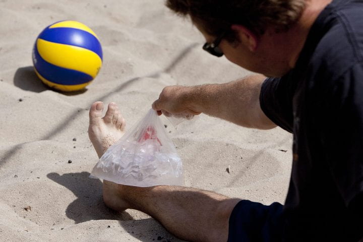 Beach volleyball player icing their ankle