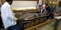 American and Egyptian researchers carrying a sarcophagus
