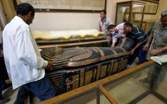 American and Egyptian researchers carrying a sarcophagus