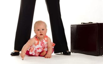 Baby sitting at the feet of their mother next to a briefcase