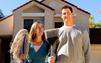 A woman holding a mop and a man holding a broom