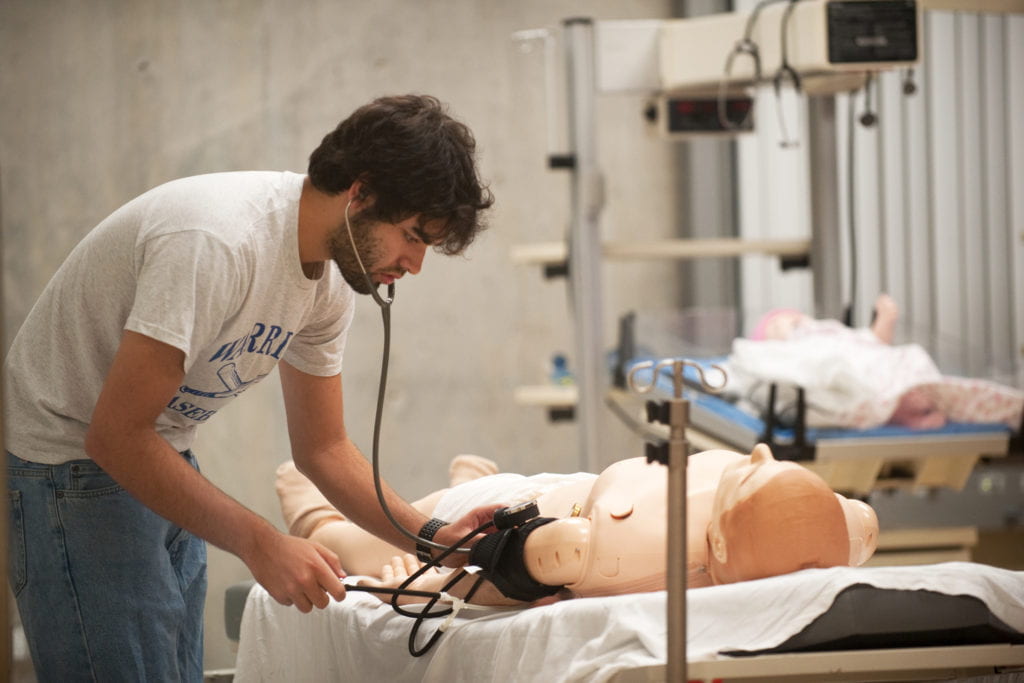 Colin McCrimmon performs a vital signs test on a medical simulation patient