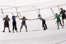 Incoming doctoral students traverse a 360-foot-long rope course 50 feet in the air on the fields of the Anteater Recreation Center