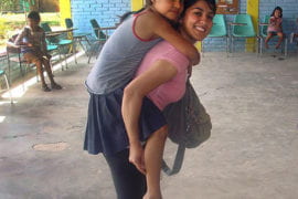 Marym Mohammady gives a piggyback ride to an orphan in Nuevo Paraiso