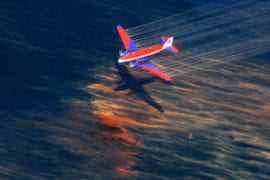 A fixed-wing aircraft releases dispersant over the oil spill