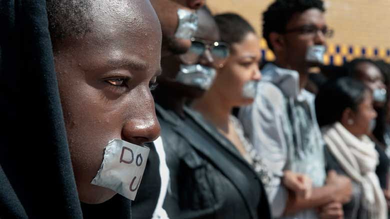 Protesters wear duct tape over their mouths with "Do UC us?" written on top