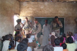 U.S. military personnel help distribute school supplies