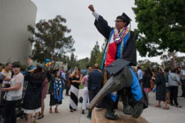 Social policy & public service grad Anthony Pham poses for a picture atop the anteater statue
