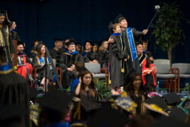 A grad utilizes a selfie stick during the School of Social Sciences commencement.