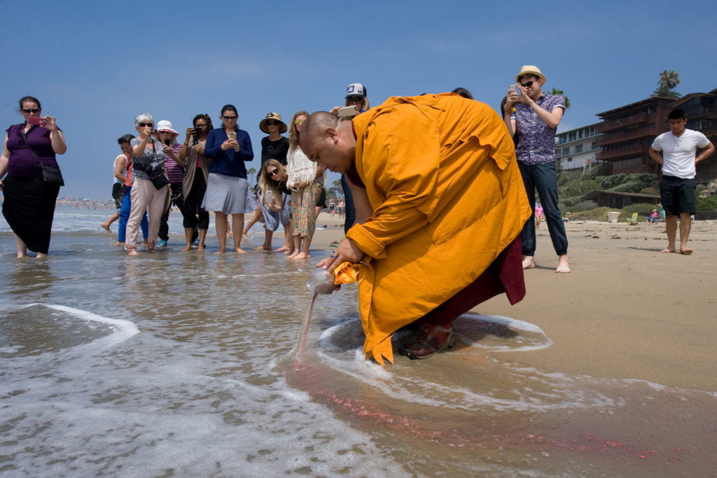 At Corona del Mar State Beach on Wednesday, a Tibetan monk releases into the ocean sand from a mandala created at UCI