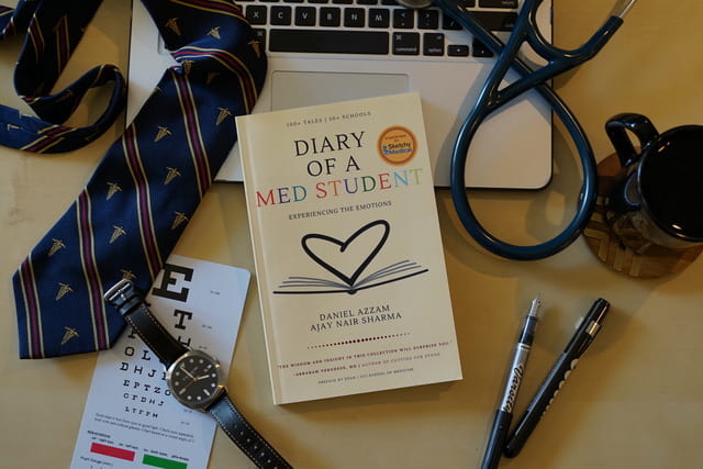 Diary of a Med Student book surrounded by a tie, laptop and stethoscope