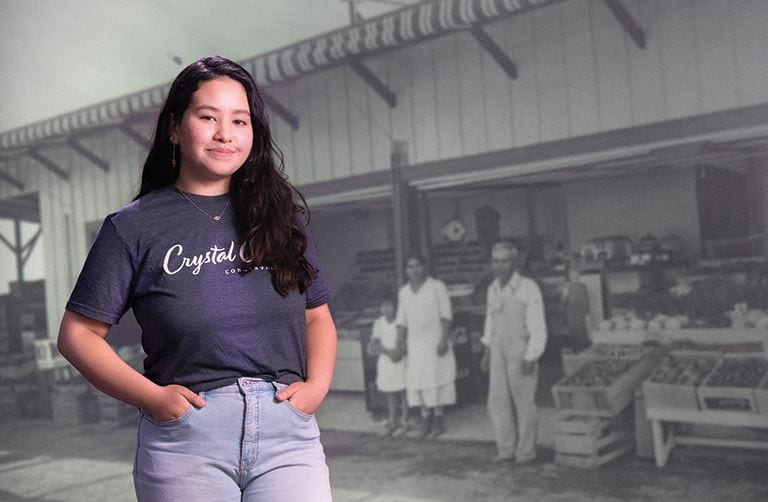 Rehana Morita standing in front of black and white image featuring Don Miyada, Crystal Cove State Park, Oral History Collection