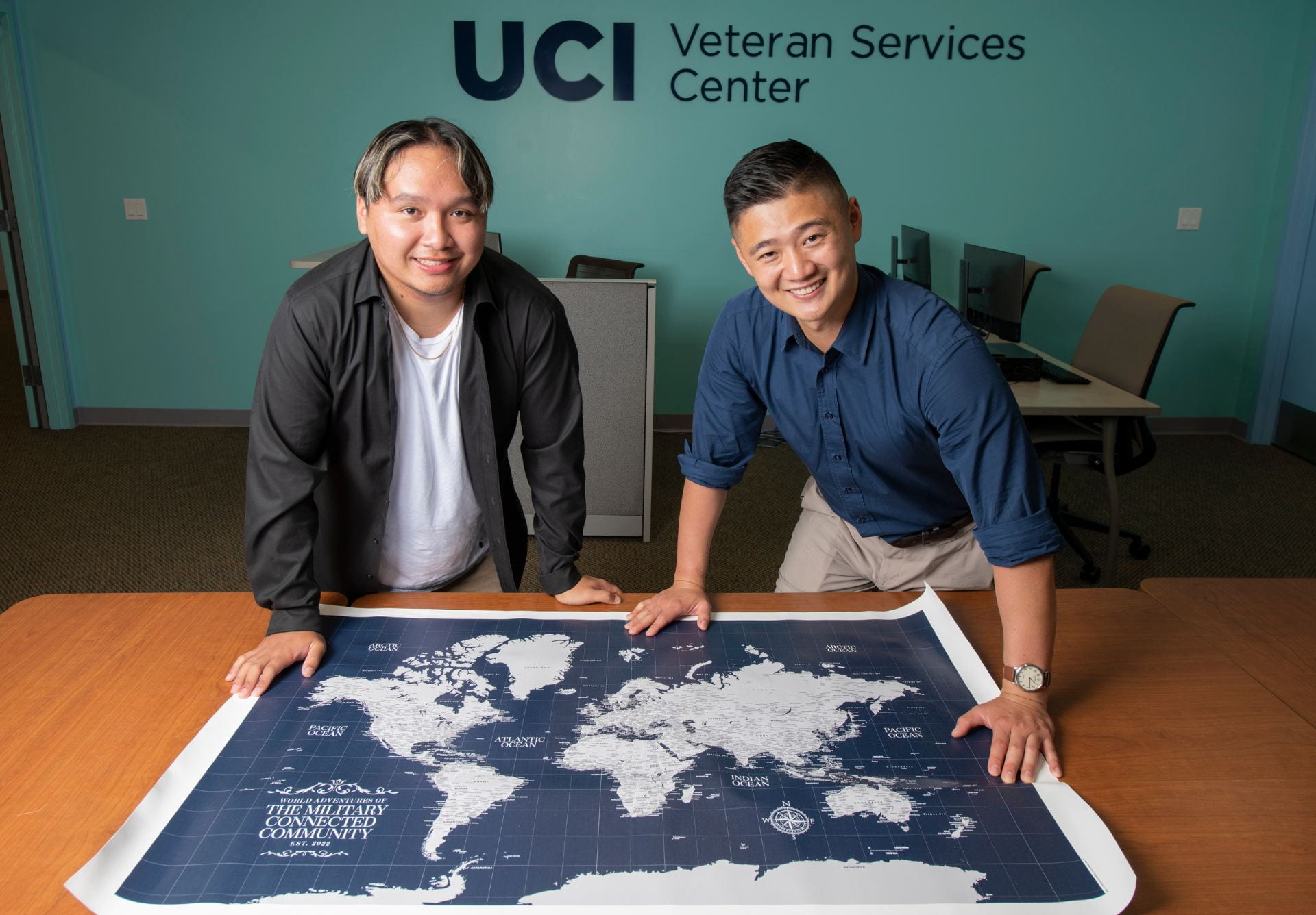 Emmanuel “David” Sangalang Delacruz (left) and Raymond Lim, a grad student in accounting and secretary of the MCC’s board, display the world map on which visitors to the campus’s Veteran Services Center are invited to pinpoint where they grew up and where they’ve been around the globe.