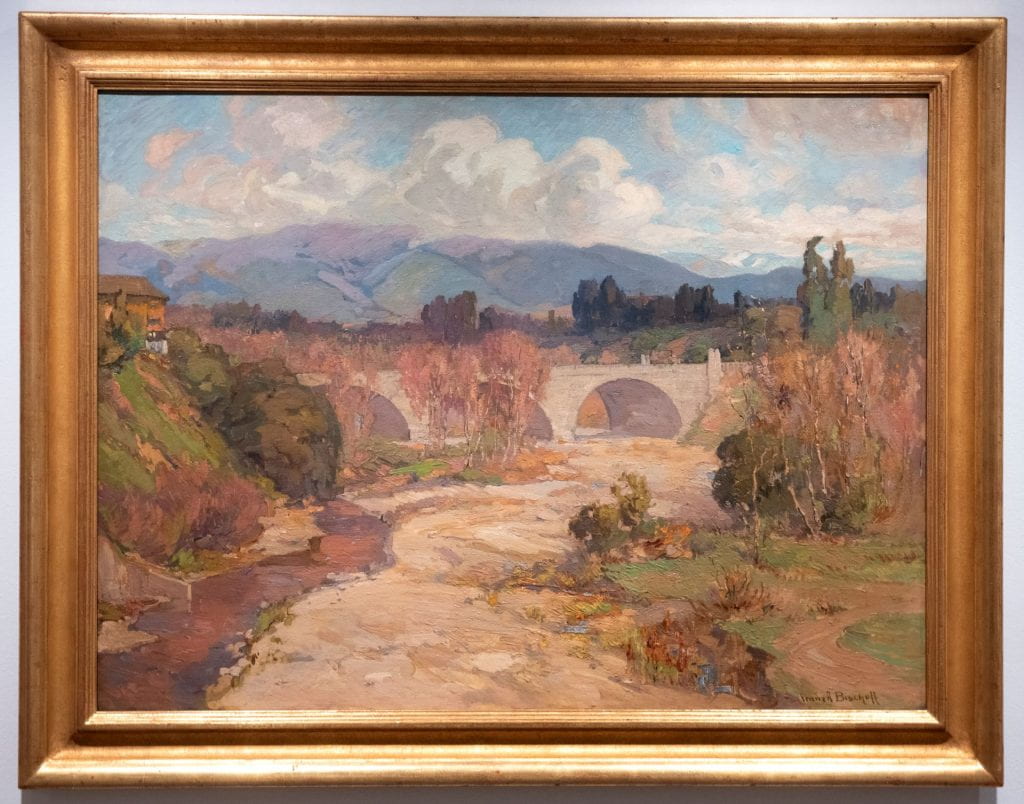 A parched creek bed and stream in a painting created in 1912 by Franz A. Bischoff “Arroyo Seco Bridge."