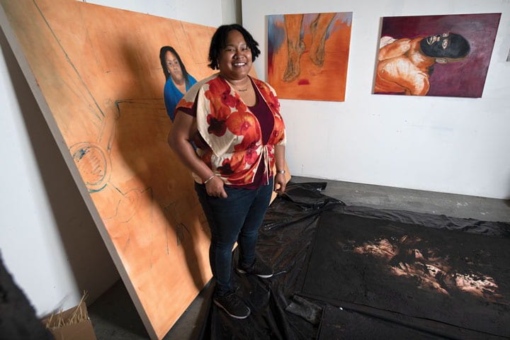Khadijah Silva stands next to her art