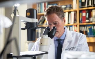 Richard Van Etten looking into a microscope