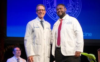 Darrys Reese receives his first physician’s white coat and a welcome from Dr. Michael J. Stamos, dean of the School of Medicine, at an Aug. 4 ceremony.