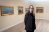 Susan M. Anderson standing in front of paintings in a gallery.