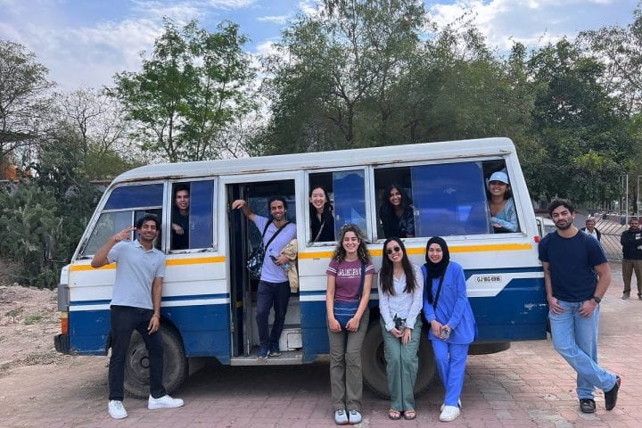 UCI medical students standing in front of a shuttle bus in India.
