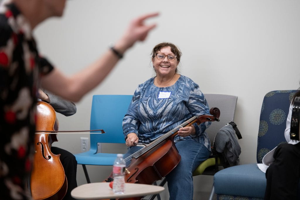 Cindy Garcia, who manages her mother’s care after the older woman experienced a series of ministrokes, saws away on a cello, an instrument she had never played before.