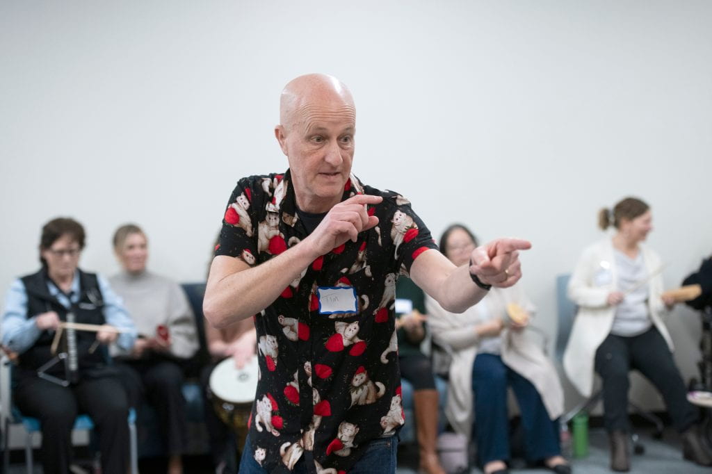 Dancing, joking and gesturing, workshop leader Tim Steiner guides a Strokestra session attended by UCI Health patients and caregivers, UCI music students and medical school faculty, and other guests.