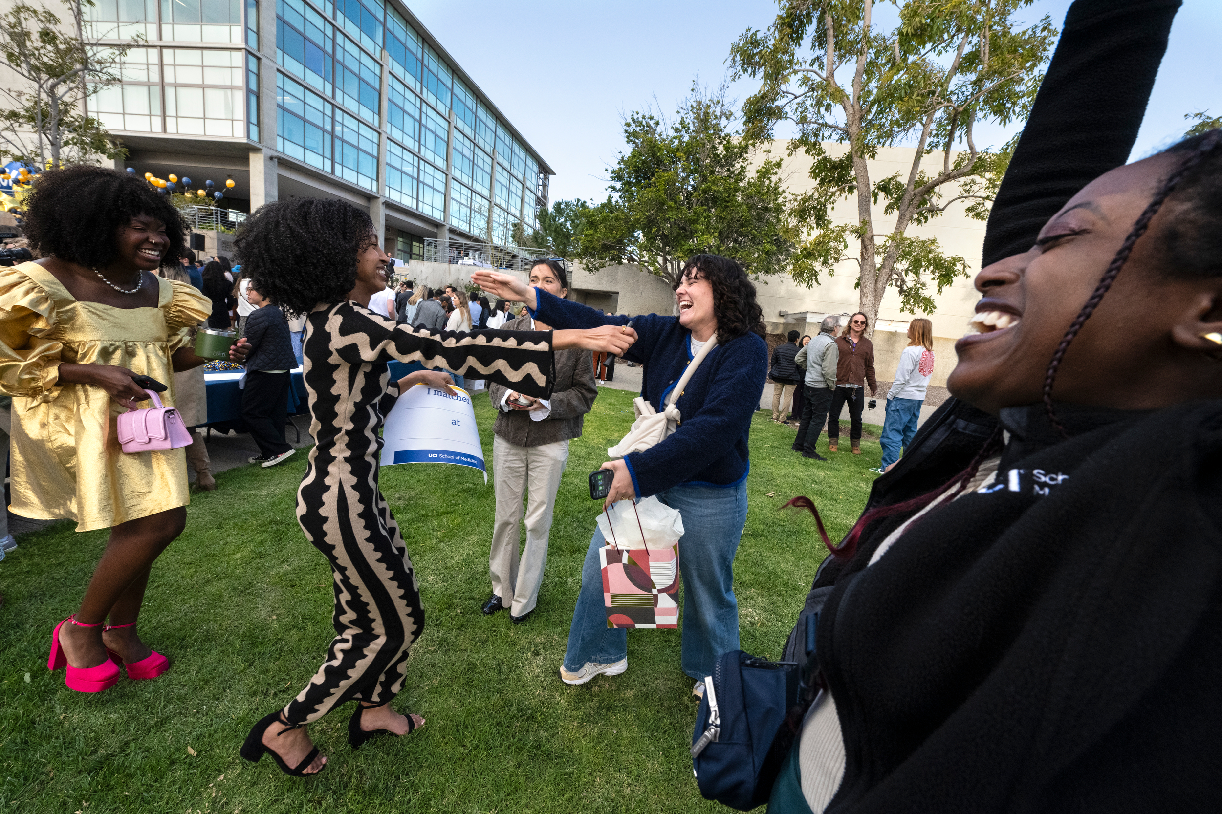 At the Match Day event, Clare Dasilva (left, in gold dress) and Gabby Rodriguez (right, in blue sweater) celebrate with graduating UCI medical student Betty Tesfaye (center), who will be going to New York University for a residency in pediatrics.