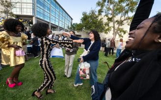 Clare Dasilva (left, in gold dress) and Gabby Rodriguez (right, in blue sweater) congratulate Betty Tesfaye (center), who will be going to New York University for a residency in pediatrics.