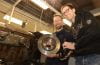 Lead study authors Adam Thomas (right) and Paulus Bauer (left) hold a brake rotor and caliper next to the lathe they and their UCI team used to measure car brake emissions.