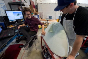 Guerrero (left) admires the handiwork of mechanical engineering major Devin Pozas, who has been preparing the 3-D printed nose cone for use in the molding of the fuselage. Steve Zylius / UCI