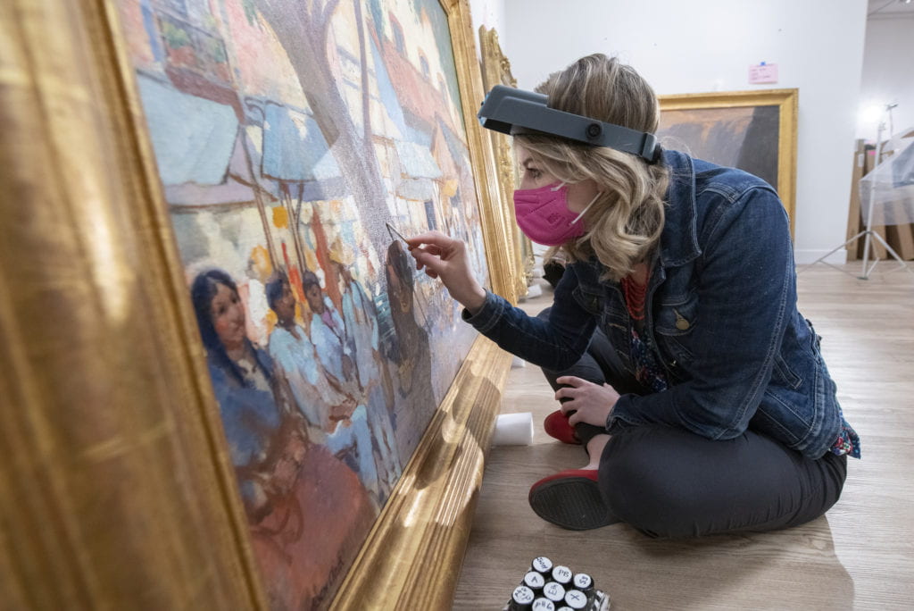 Morgan Wylder, an assistant conservator of paintings with the Balboa Art Conservation Center, carefully swabs a painting that’s being prepared for display at the Institute and Museum of California Art.